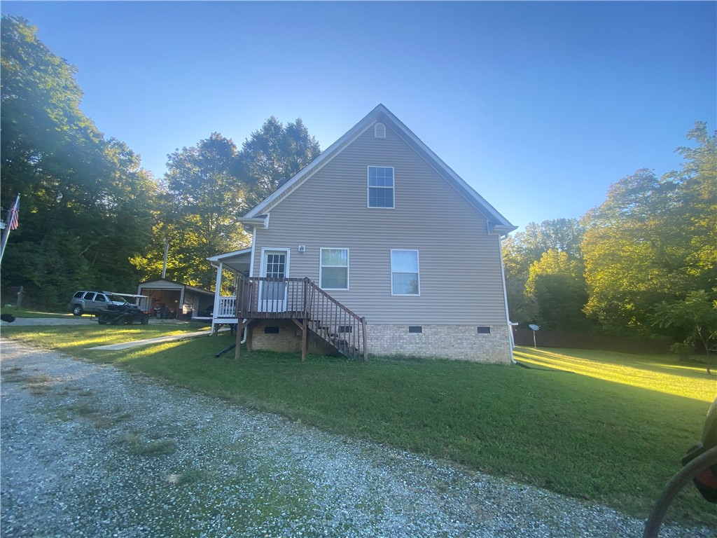 An elevated side view showcases the vinyl siding and stone foundation of this country home.