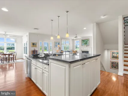 a kitchen with stainless steel appliances granite countertop a sink a stove a dining table and chairs with wooden floor