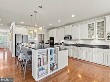 a open kitchen with stainless steel appliances granite countertop a stove top oven a large island a dining table and chairs