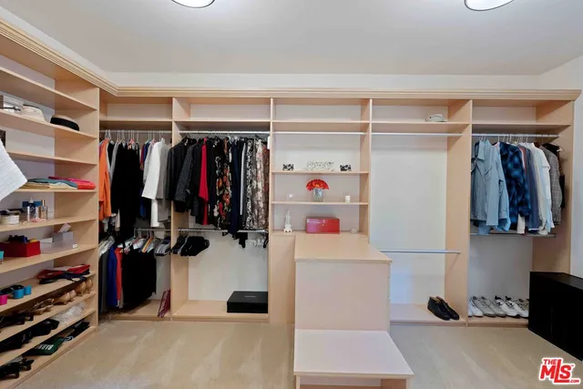 a view of walk in closet with clothes and shoes