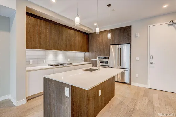 a kitchen that has a sink a refrigerator and a stove top oven