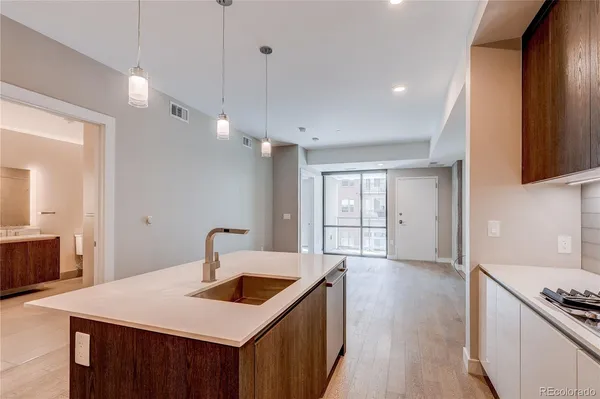 a kitchen with a stove a sink a refrigerator and wooden floor