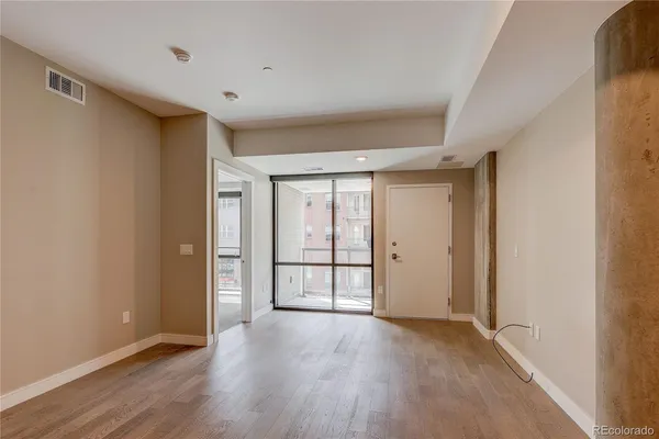 a view of an empty room with wooden floor and a window