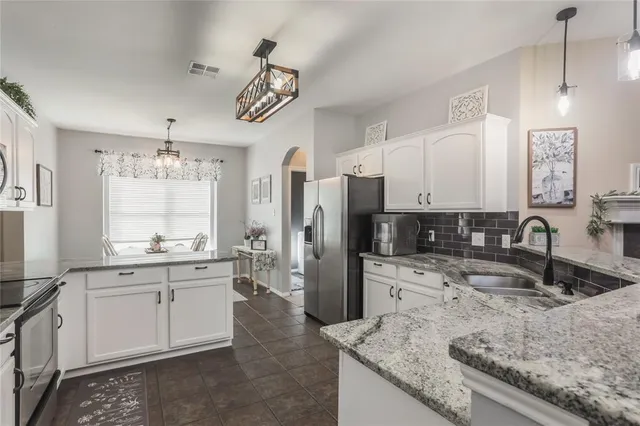 a large kitchen with granite countertop a sink a counter space appliances and cabinets