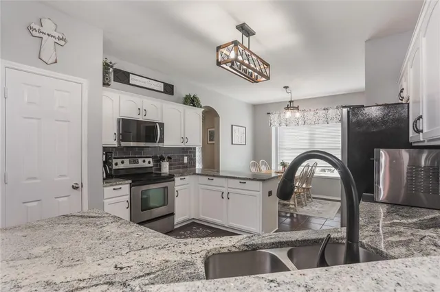 a kitchen with stainless steel appliances granite countertop a sink a stove and a refrigerator