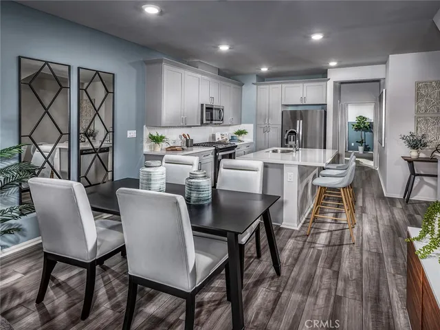 a kitchen with stainless steel appliances granite countertop a table chairs sink refrigerator and microwave