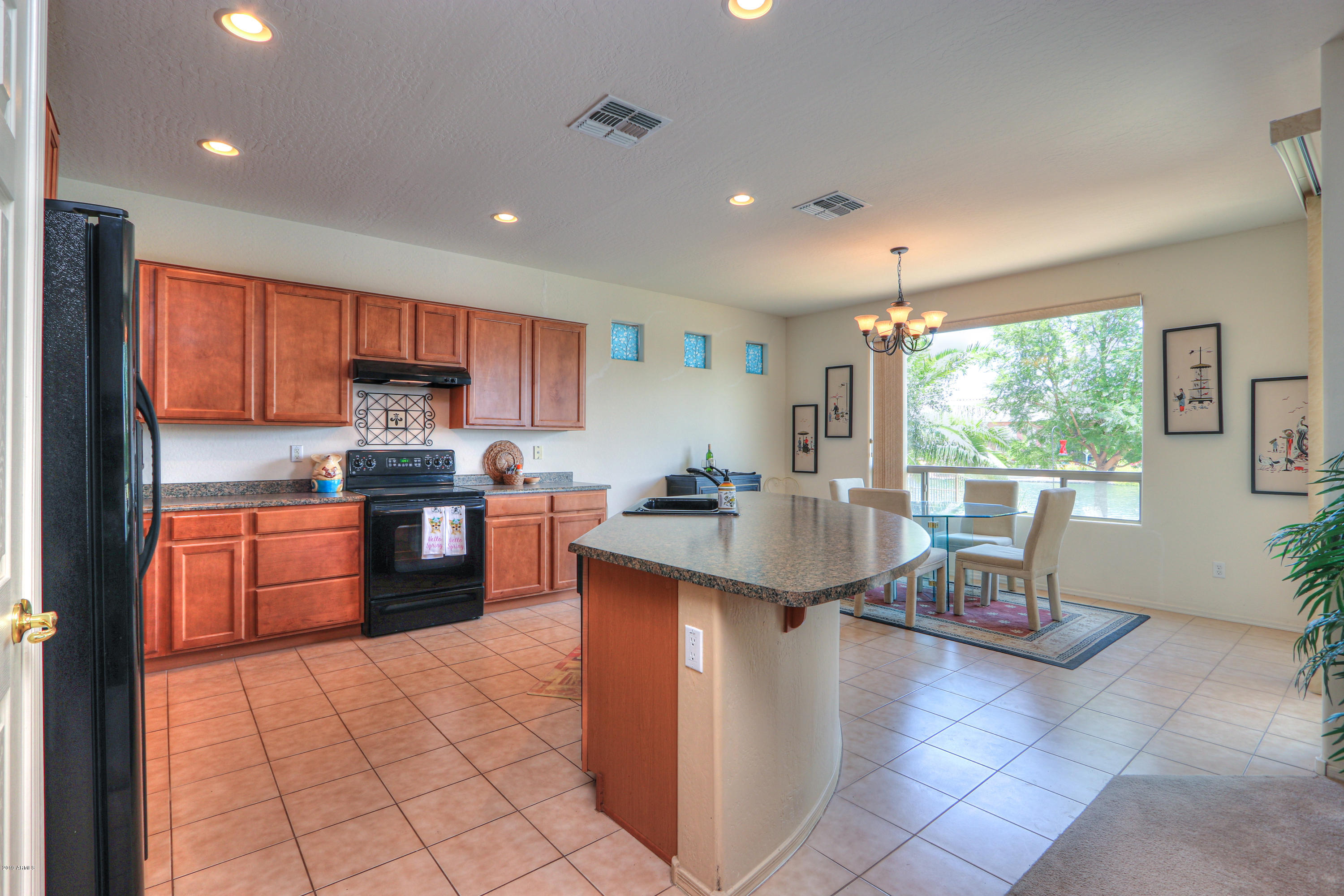 42485 Abbey Road Maricopa, AZ 85138 - Photo 14 of 74 a kitchen with stainless steel appliances kitchen island granite countertop a refrigerator a stove top oven and a sink with island