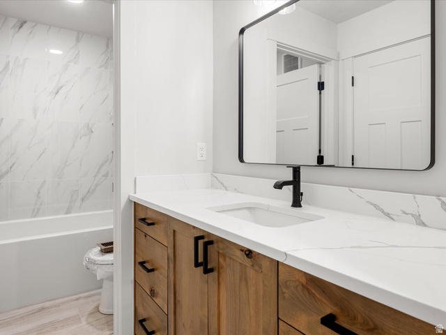 1159 North Broad Hollow Road Garden City, UT 84028 - Photo 33 of 55 Modern bathroom featuring a wood-finish vanity with black hardware, a white countertop with gray veining, and an undermount sink with a matte black faucet
