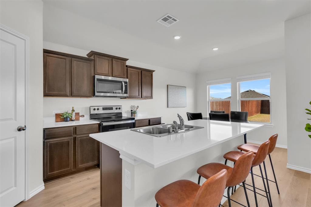 6513 Waterfall Lane Princeton, TX 75407 - Photo 5 of 35 a kitchen with stainless steel appliances a sink a stove a refrigerator cabinets and dining table