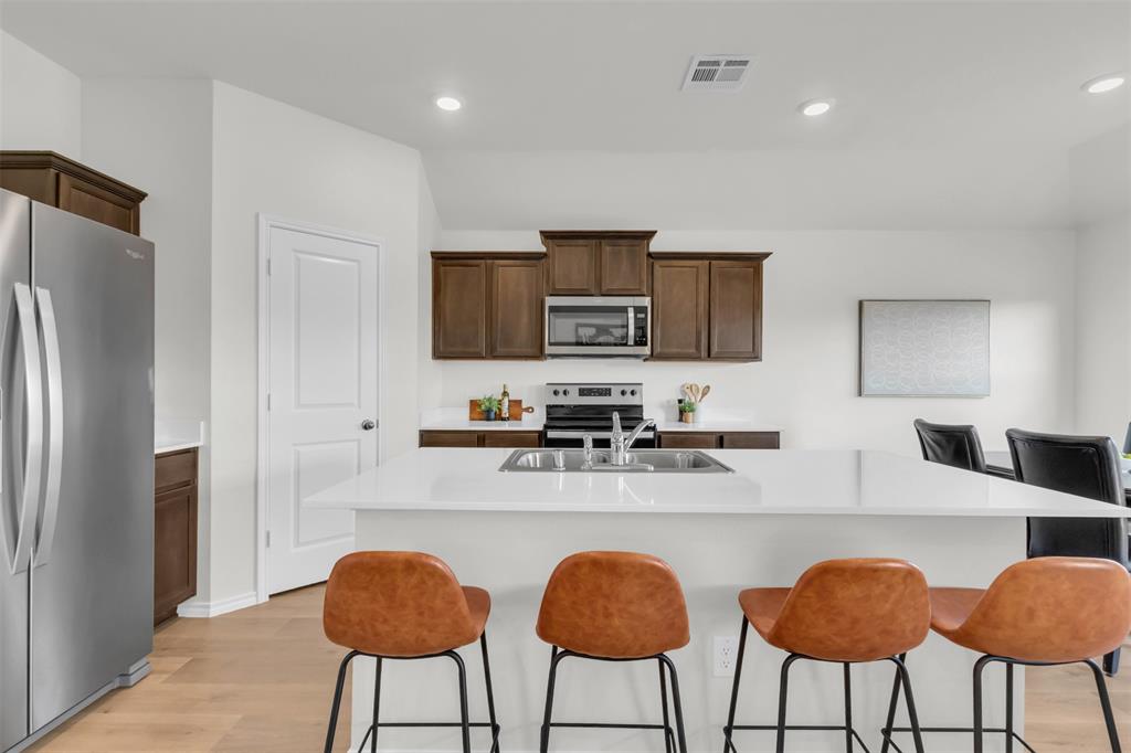 6513 Waterfall Lane Princeton, TX 75407 - Photo 6 of 35 a kitchen with stainless steel appliances granite countertop a refrigerator a stove a sink and chairs