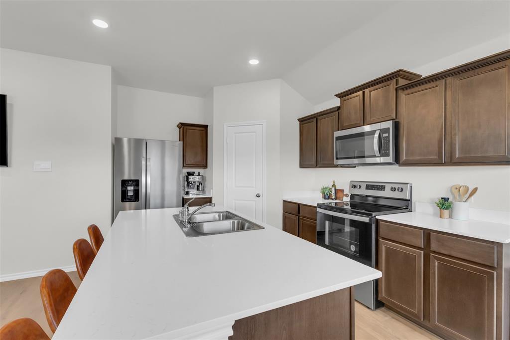 6513 Waterfall Lane Princeton, TX 75407 - Photo 8 of 35 a kitchen with stainless steel appliances a stove microwave and sink