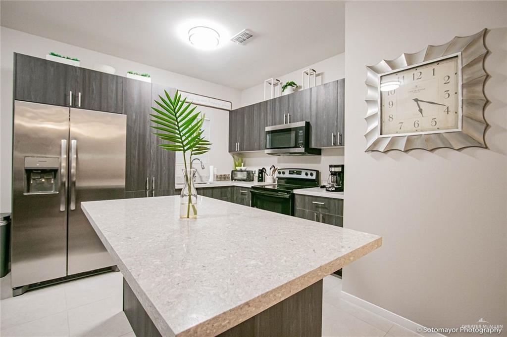 5609 Swallow Avenue, Unit 1 Mission, TX 78573 - Photo 7 of 15 Kitchen with stainless steel appliances, light tile patterned floors, dark brown cabinets, a center island, and modern cabinets