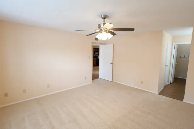 a view of an empty room with a chandelier fan