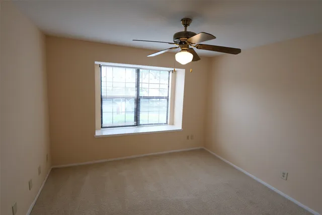 an empty room with a window and a fan