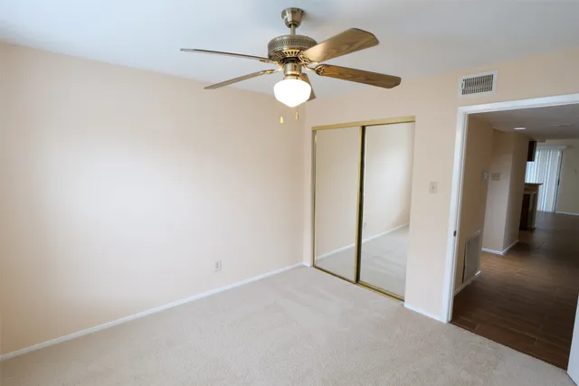 a view of an empty room with a chandelier fan