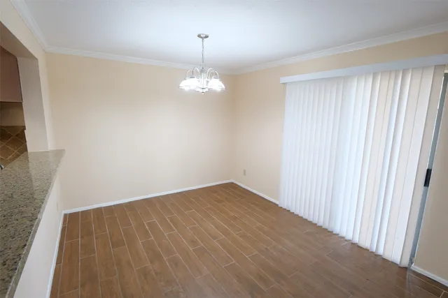 an empty room with wooden floor and chandelier