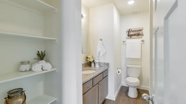 a bathroom with a granite countertop toilet a sink and a mirror