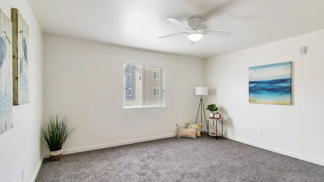 an empty room with windows and ceiling fan