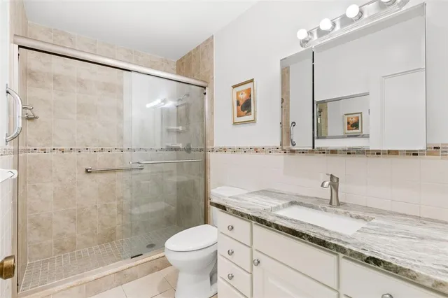 a bathroom with a granite countertop sink toilet a mirror and shower