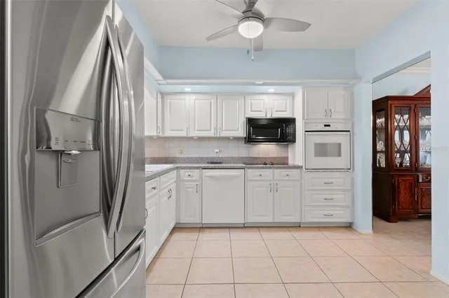 a kitchen with white cabinets and refrigerator