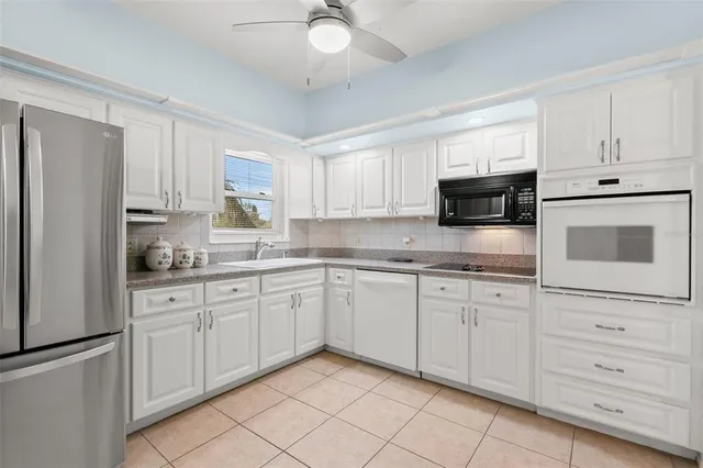 a kitchen with granite countertop white cabinets stainless steel appliances and a sink