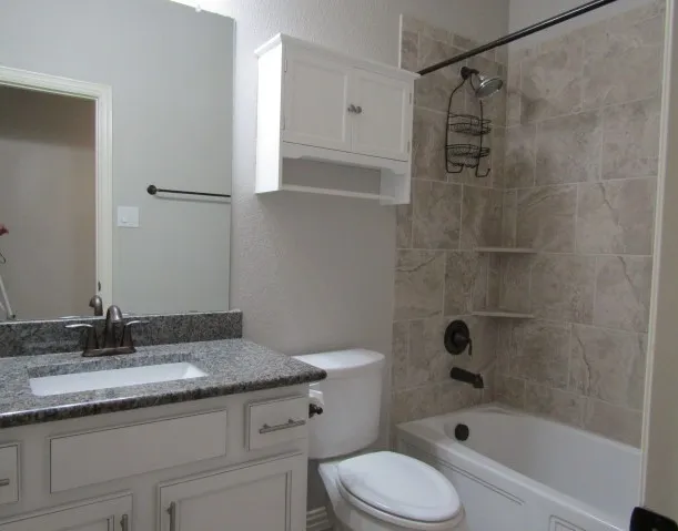 a bathroom with a granite countertop sink a toilet and shower