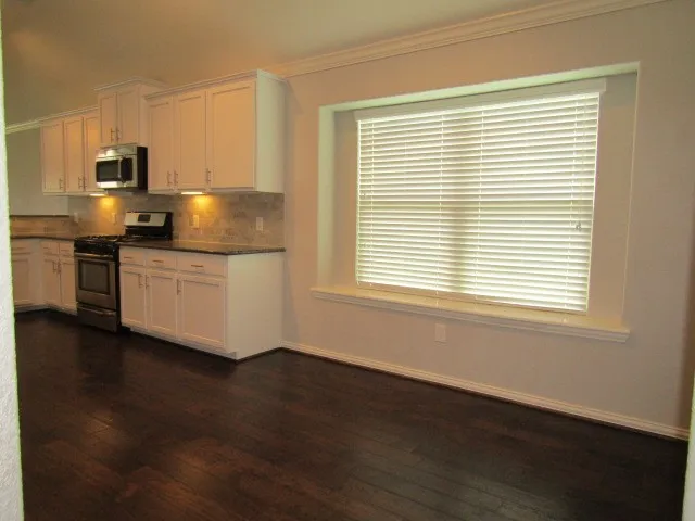 a kitchen with stainless steel appliances a sink a stove a microwave and wooden floor