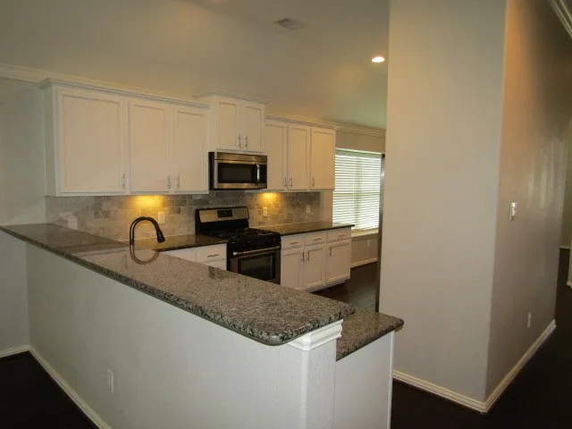 a kitchen with granite countertop stainless steel appliances a sink a stove and a refrigerator