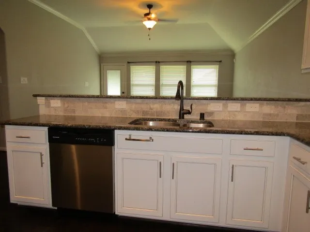 a kitchen with granite countertop white cabinets and a sink