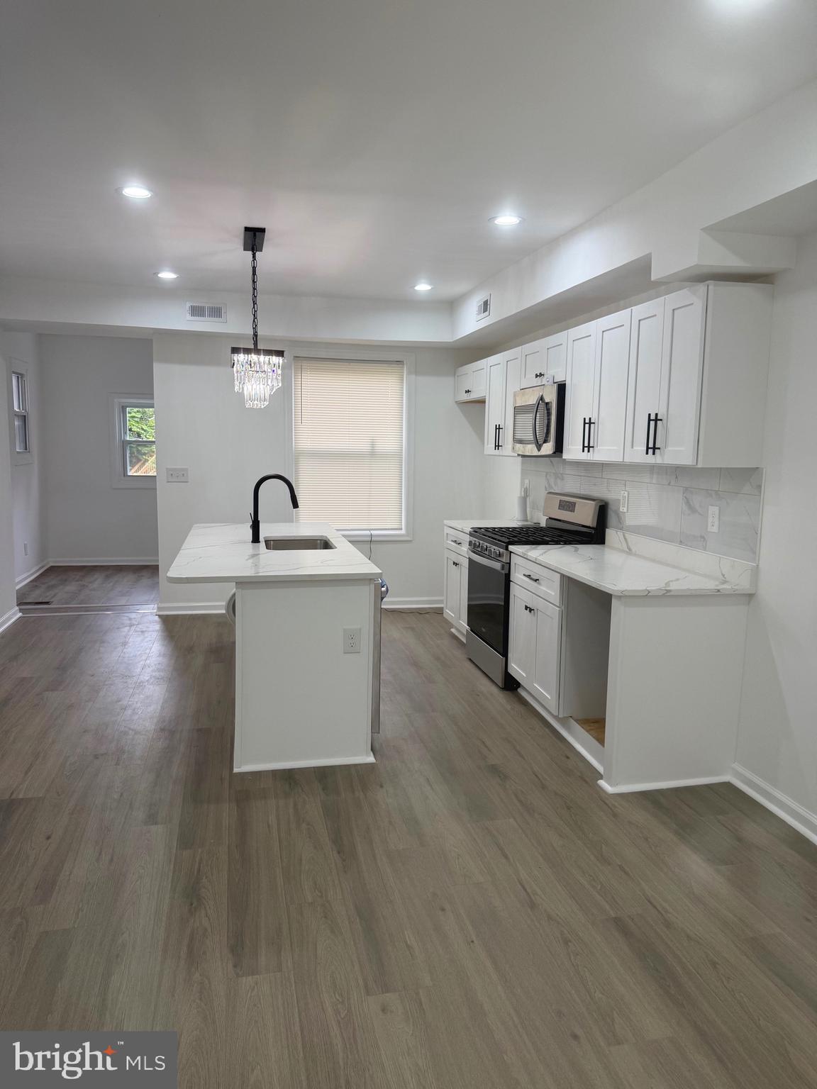 4803 Cordelia Avenue Baltimore, MD 21215 - Photo 4 of 39 a large kitchen with stainless steel appliances kitchen island a large counter top and wooden floors