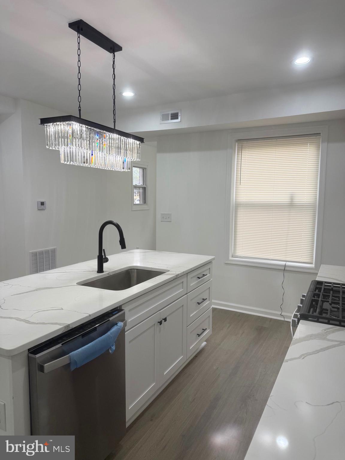 4803 Cordelia Avenue Baltimore, MD 21215 - Photo 5 of 39 a kitchen with stainless steel appliances granite countertop a sink a stove a dining table and chairs with wooden floor