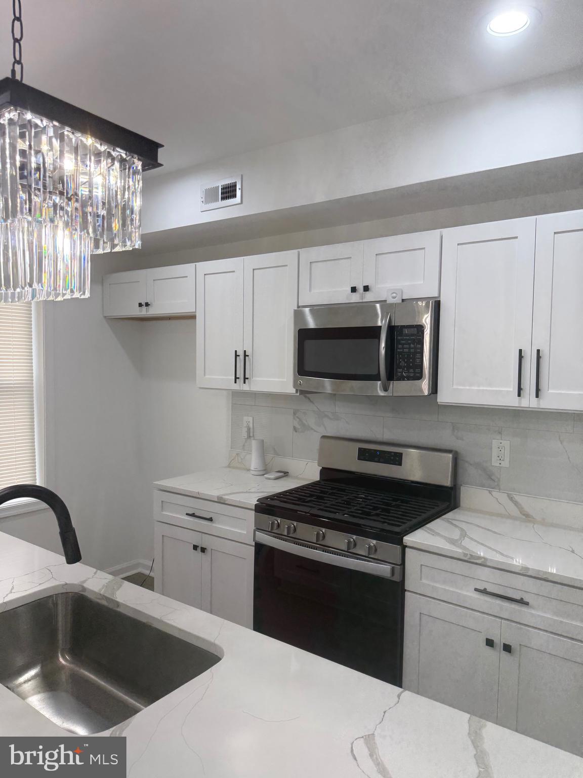 4803 Cordelia Avenue Baltimore, MD 21215 - Photo 8 of 39 a kitchen with stainless steel appliances granite countertop a sink stove and microwave