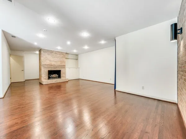 an empty room with wooden floor fireplace and windows