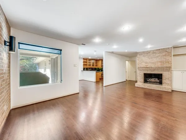 an empty room with wooden floor fireplace and windows