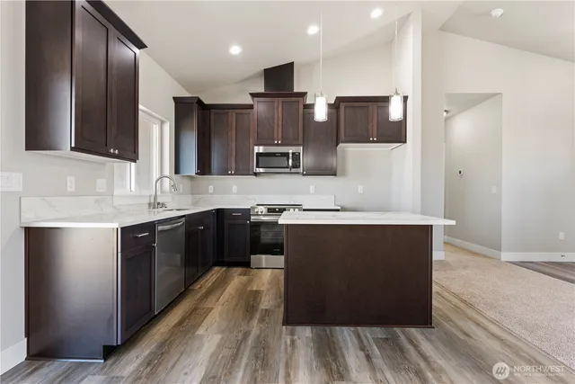 a kitchen with stainless steel appliances granite countertop wooden cabinets a refrigerator and a sink