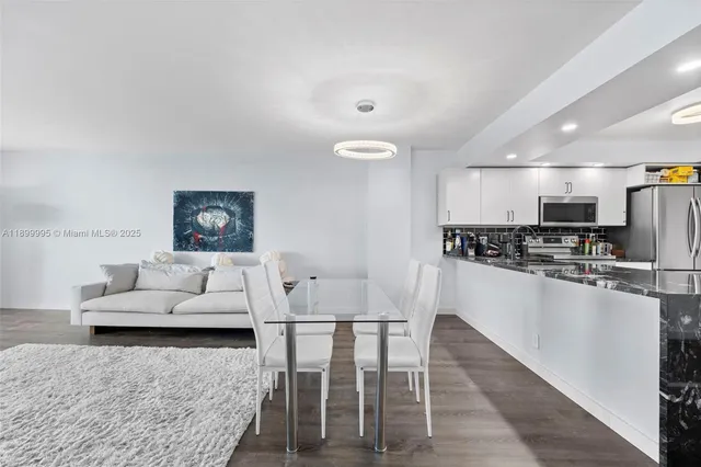 a living room with stainless steel appliances furniture and a kitchen view
