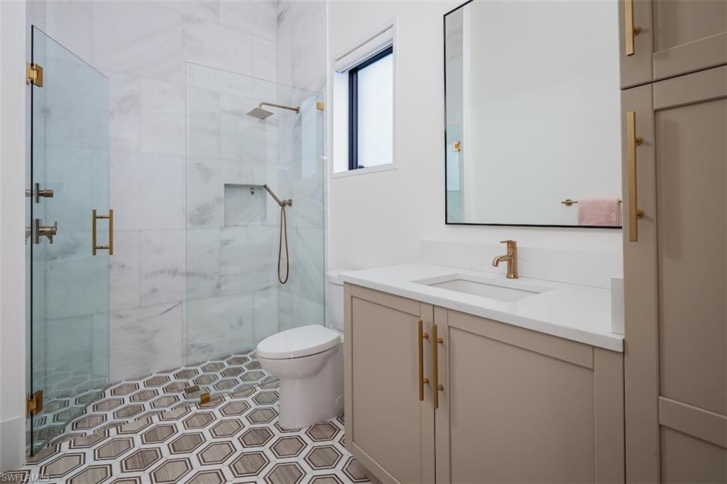 728 Carica Road Naples, FL 34108 - Photo 19 of 26 a bathroom with a granite countertop sink toilet and shower