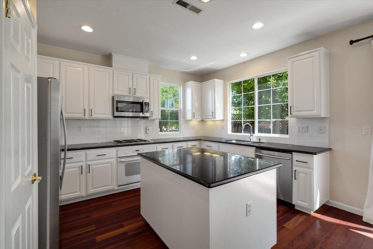 9145 Desiderio Way Gilroy, CA 95020 - Photo 14 of 33 a kitchen with granite countertop a sink dishwasher stove and refrigerator with wooden floor