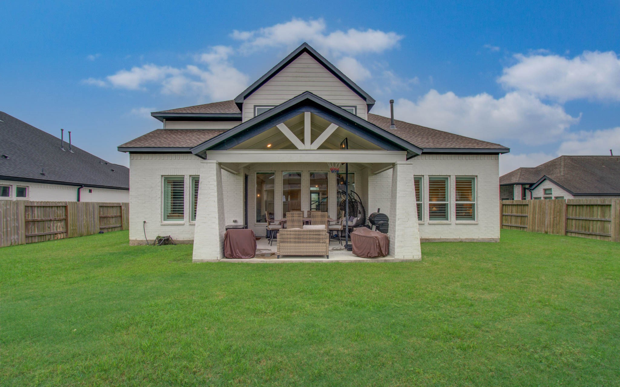 4211 Limestone Terrace Manvel, TX 77578 - Photo 33 of 33 This photo showcases a charming house with a spacious, well-maintained backyard. The home features a covered patio area perfect for outdoor relaxation and entertaining. The fenced yard provides privacy, and the exterior has a fresh, modern appearance with its light-colored siding and clean lines.