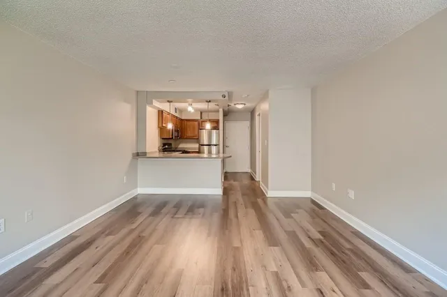 a view of a big room with wooden floor and a kitchen