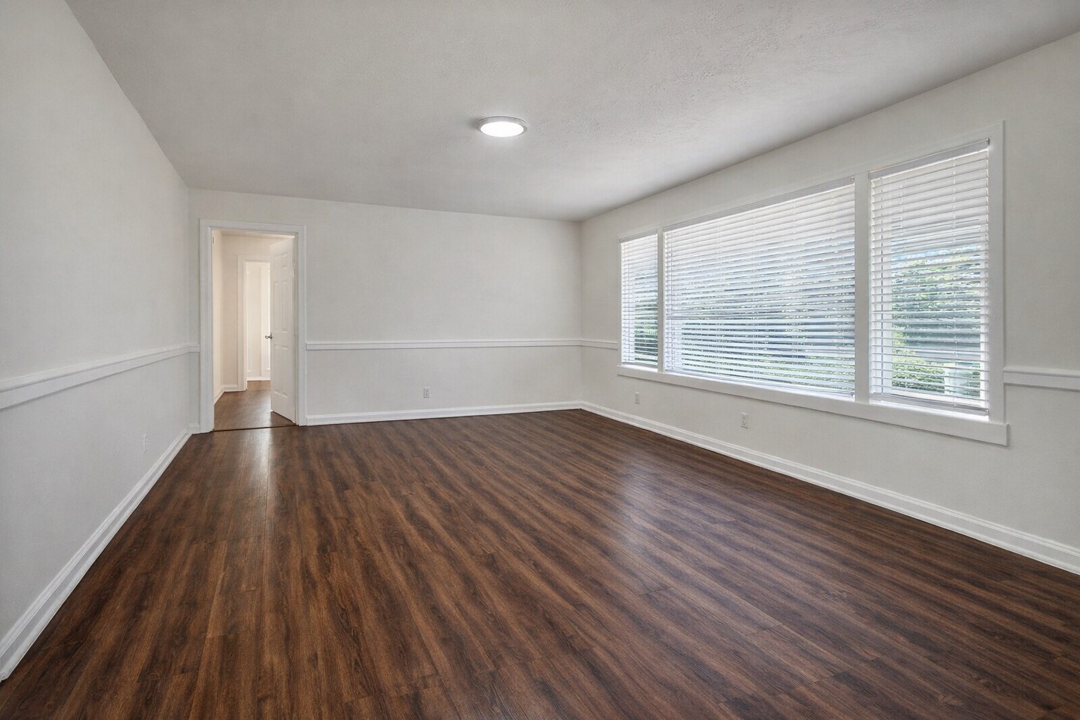 209 West Alfred Street El Campo, TX 77437 - Photo 3 of 15 an empty room with wooden floor and windows