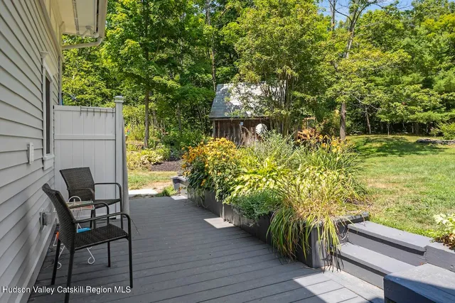 a backyard of a house with table and chairs potted plants and large tree