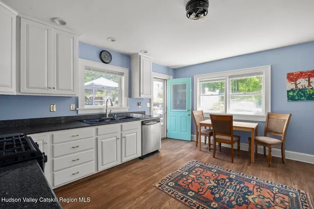 a open kitchen with granite countertop a dining table chairs and white cabinets