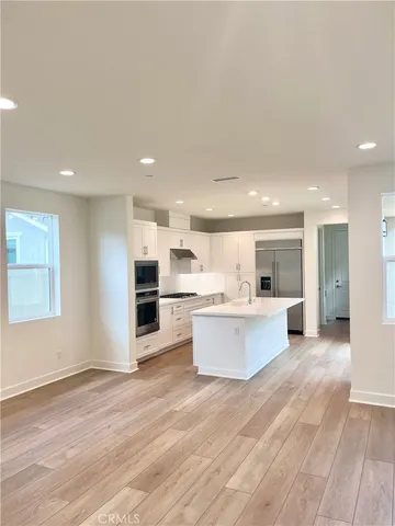 a large white kitchen with kitchen island a sink a center island stainless steel appliances and a cabinets