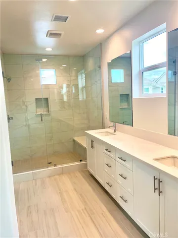 a bathroom with a double vanity sink mirror and shower