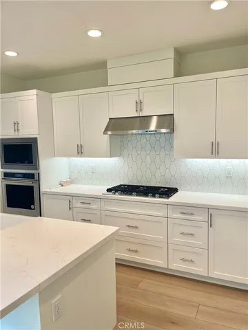 a kitchen with stainless steel appliances white cabinets and a refrigerator