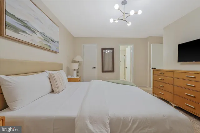 a bedroom with a bed a flat screen tv and a chandelier