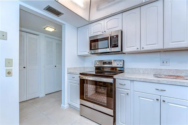 a kitchen with stainless steel appliances granite countertop white cabinets a stove top oven