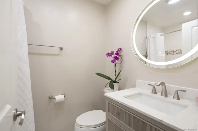 a bathroom with a sink vanity mirror and toilet
