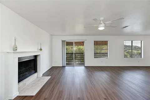 an empty room with wooden floor fireplace cabinet and windows